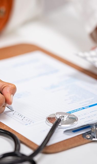 Closeup of woman hands writing medicine inventory. Close up hands of female doctor writing the medicines to be taken on the preoperative model sheet. Pharmacist checking inventory at hospital pharmacy.